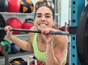 Femme souriante soulevant une barre au gym MissFit Montréal