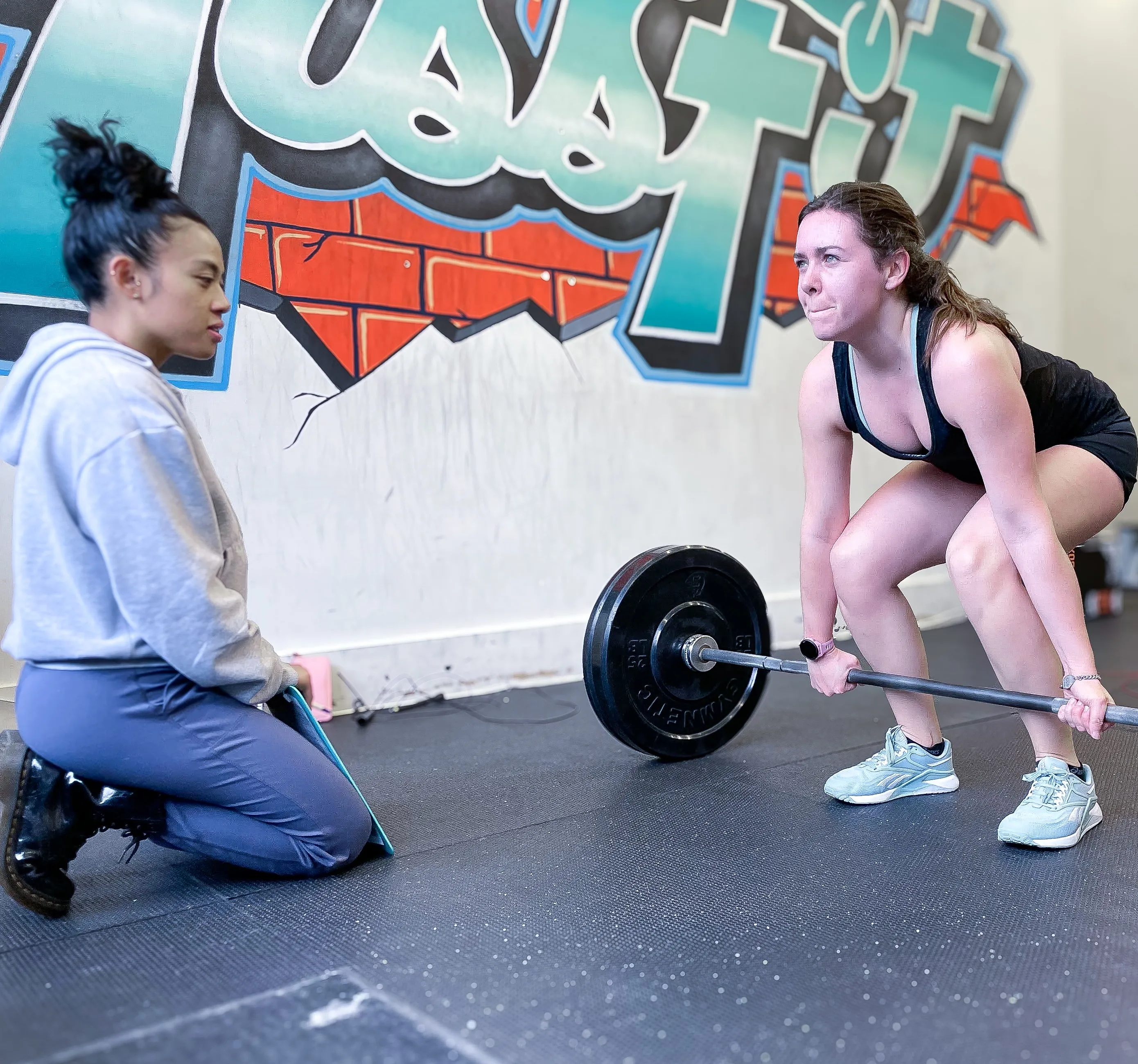 Une coach sportive accompagne une membre sur un soulevé de terre au studio MissFit Montréal